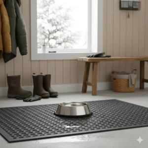 A durable dog bowl with a rubber grip base sitting on a winter mat in a Canadian entryway or mudroom.